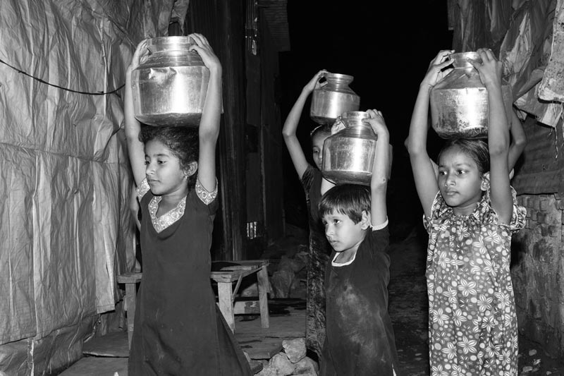 Urban Drinking Water Challenges - Girl children carrying headloads of water in the night in an unauthorized colony in Mumbai, Maharashtra